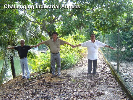 Cleaning Industrial Abuses Three residents of Bukit Koman, Malaysia, mark the distance between a neighbor's fence and a water-filled mining pit.